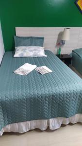 uma cama verde com dois certificados em cima em Casa Klos - Quartos amplos em Curitiba