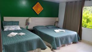 1 dormitorio con 2 camas y pared verde en Casa Klos - Quartos amplos en Curitiba