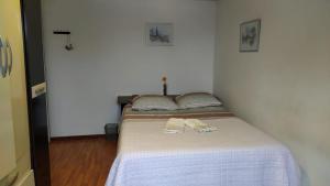 Una cama en una habitación con dos zapatillas. en Casa Klos - Quartos amplos, en Curitiba