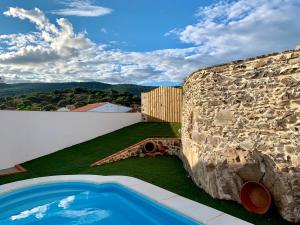a backyard with a stone wall and a swimming pool at Casa Rural Sierra Tórtola 2 in Hinojales