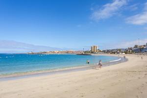 a group of people walking on the beach at Home2Book Sea Front Vista Marina, Los Cristianos in Arona