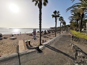 plaża z palmami i ludźmi na piasku w obiekcie Home2Book Sea Front Vista Marina, Los Cristianos w Aronie