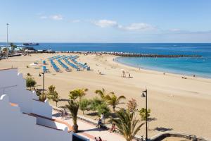 a beach with umbrellas and people on the beach at Home2Book Sea Front Vista Marina, Los Cristianos in Arona