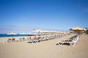 a row of chairs and umbrellas on a beach at Home2Book Sea Front Vista Marina, Los Cristianos in Arona