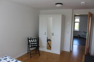 Habitación con armario blanco y silla negra. en Turmfalke en Bad Sülze