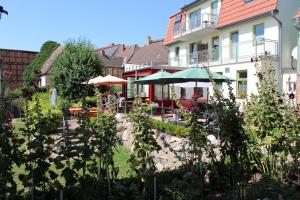 Bad Sülze的住宿－Turmfalke，一座花园,在一座建筑前设有桌子和遮阳伞