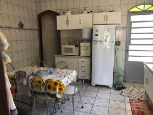 a kitchen with a table and a white refrigerator at Casa do Descanso em São Bento do Sapucaí in São Bento do Sapucaí