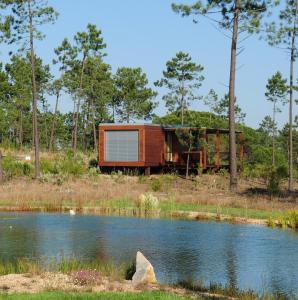 a cabin in the woods next to a river at Cocoon Eco Design Lodges in Carvalhal