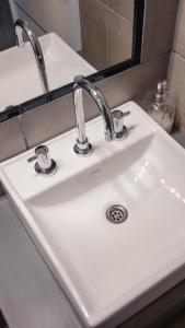 a white sink with two faucets and a mirror at Juana House in San Juan
