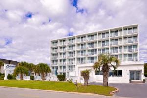 a white building with palm trees in front of it at Cabana Shores Hotel in Myrtle Beach