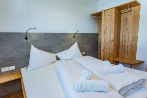 Una gran cama blanca con toallas encima. en Happy Aich 3 by Alpenidyll Apartments, en Aich