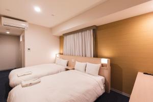 京都市にある相鉄フレッサイン 京都四条烏丸のベッド2台と窓が備わるホテルルームです。
