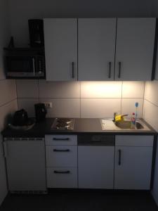 eine kleine Küche mit weißen Schränken und einem Waschbecken in der Unterkunft Ferienwohnung bei Wessels in Schloß Holte-Stukenbrock