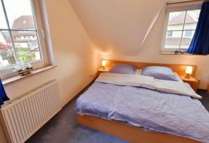 a bedroom with a bed and two windows at Am Deich 41 in Zingst