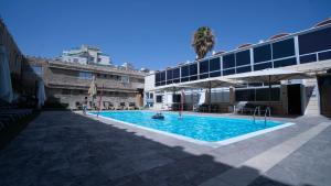 ein Pool mit Sonnenschirmen neben einem Gebäude in der Unterkunft Rich Boutique Hotel in Eilat
