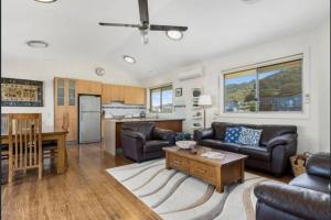 a living room with couches and a kitchen at Beachside Bliss with Secure yard l Pet Friendly in Apollo Bay
