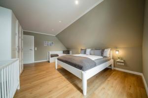 a bedroom with a white bed and wooden floors at Ferienhaus Seeblick - 78913 in Gammendorf