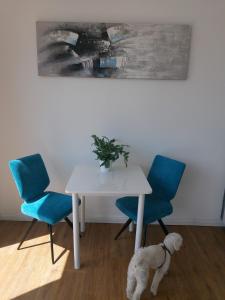uma mesa branca e duas cadeiras azuis e um cão branco em Casa Kronengarten Nr 16 em Hilden
