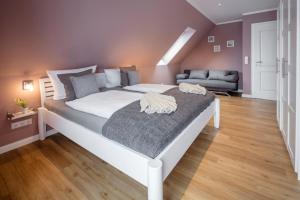 a large white bed in a room with a couch at Ferienhaus Seeblick - 78913 in Gammendorf