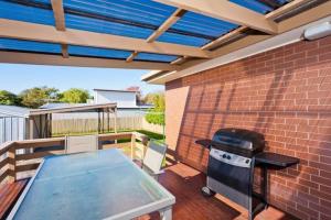 a patio with a table and a grill on a brick wall at Intrigue FREE WI-FI in Apollo Bay