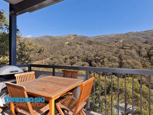 a wooden table and chairs on a balcony with a view at Elevation 5 in Thredbo