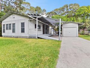 a white house with a porch and a garage at Bella on Boreen by Discover Stradbroke in Point Lookout