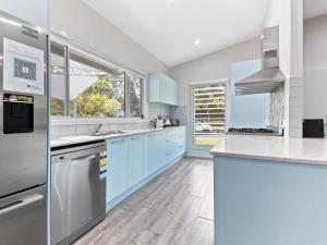 a kitchen with blue cabinets and white counter tops at Bella on Boreen by Discover Stradbroke in Point Lookout