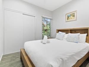 a bedroom with a large white bed and a window at Bella on Boreen by Discover Stradbroke in Point Lookout +9 photos
