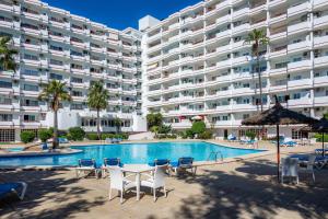 a large apartment building with a swimming pool and chairs at Alcudia Sea Apartment in Alcudia