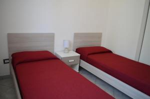2 posti letto in una piccola stanza con lenzuola rosse di Le Zagare Case Vacanza a Cropani