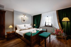 a bedroom with a large bed with green curtains at Hotel Baron in Jelenia Góra