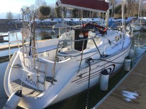 a white boat is docked at a dock at Barca a vela sul lago Maggiore in Locarno