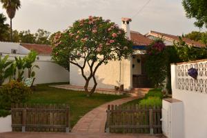 a house with a fence and a tree with pink flowers at Villa Isabelita in Torremolinos