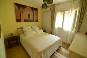 una camera da letto con un letto bianco e una finestra di Villa Isabelita a Torremolinos