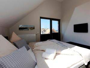 a bedroom with a white bed and a window at Ostsee - Appartement Nr 50 "Meerblick" am Yachthafen im Strand Resort in Heiligenhafen