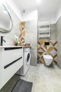 Un baño con lavadora y un inodoro. en Apartamenty Przy IV Śluzie - Green, en Bydgoszcz
