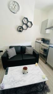 a living room with a black couch and a table at BVapartments-queengate 3 in Huddersfield
