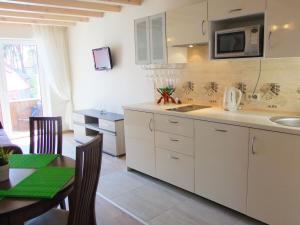cocina con armarios blancos, mesa y microondas en Irinos Apartamentai en Nida