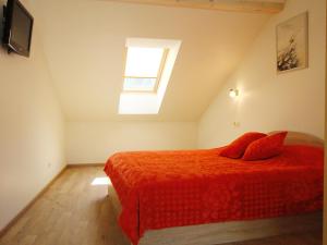 a bedroom with a bed with red sheets and a window at Irinos Apartamentai in Nida