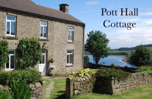 a brick house with a stone wall and a lake at Pott Hall in Masham