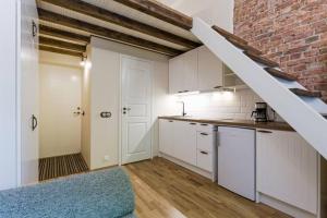 a kitchen with white cabinets and a brick wall at City Center Loft Apartment in Tallinn