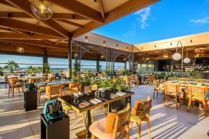 a restaurant with tables and chairs and a view of the ocean at Stella Palace Aqua Park Resort in Hersonissos