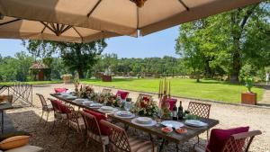 un lungo tavolo con sedie e un grande ombrellone di Villa Canto Alla Moraia 18 Emma Villas a Castiglion Fibocchi