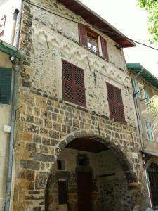 un antiguo edificio de piedra con ventanas rojas y un arco en Un studio, une Histoire : Le palais Gubernatis., en Saint-Martin-Vésubie