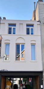 een wit gebouw met ramen aan een straat bij Residentie Fleur in De Haan