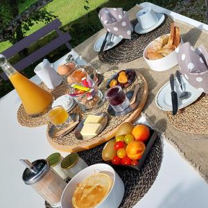 a table with a tray of food and fruit on it at La Loge du Grand Cèdre, chambre d'hôtes SoCosy in Fontcouverte