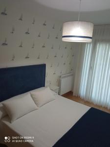um quarto com uma cama branca e uma cabeceira azul em El pisito de Lourizan em Pontevedra