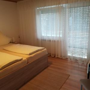 a bedroom with a bed and a window with white curtains at Landhaus Irma in Bad Füssing