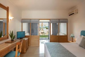 a bedroom with a bed and a desk with a television at Mitsis Ramira in Kos