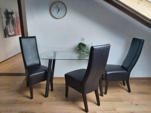 een glazen tafel met twee stoelen en een klok aan de muur bij Erholsamer Traumurlaub wo auf Bergen Schlößer wachsen in Prem